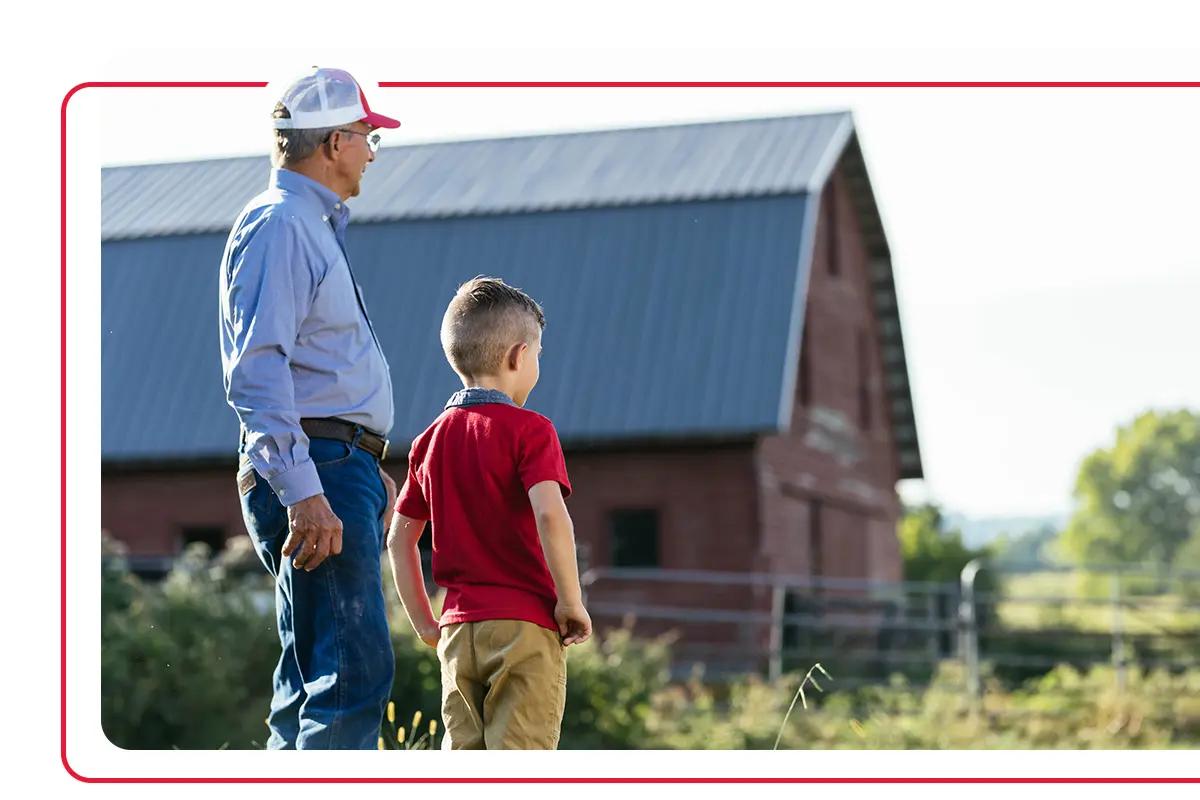 Tennessee farmer standing next to grandson and barn on farm