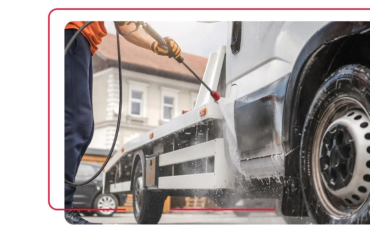 Business employee using power washer to wash dirt off commercial vehicle