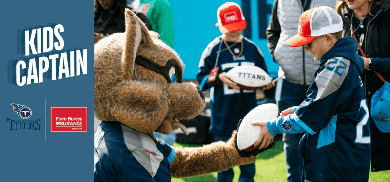 Young Tennessee Titans football fan handing football to Titans mascot on field