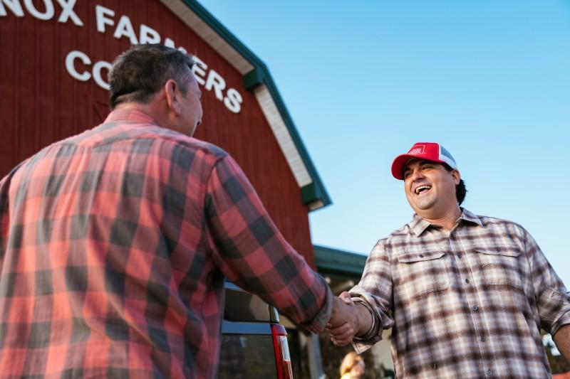 Farm Bureau insurance agent shaking hands with farmer outside of Co-Op