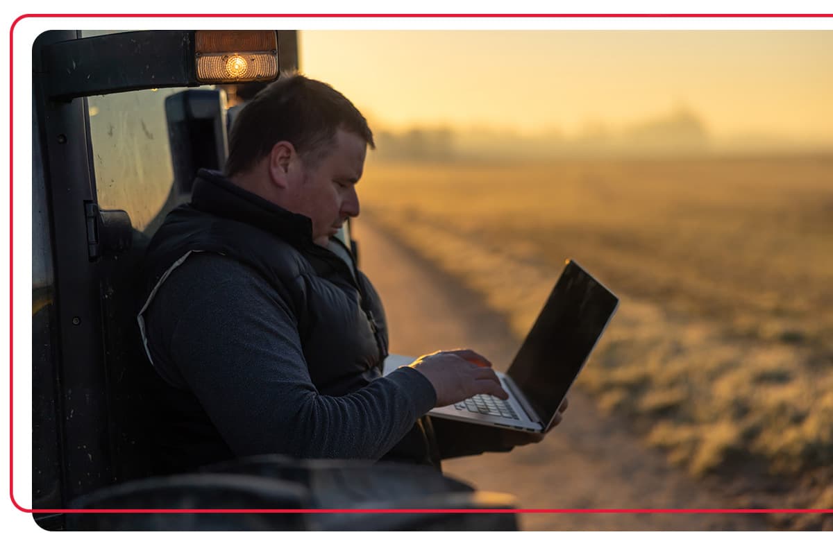 Man using his computer outside while leaned up next to his work truck