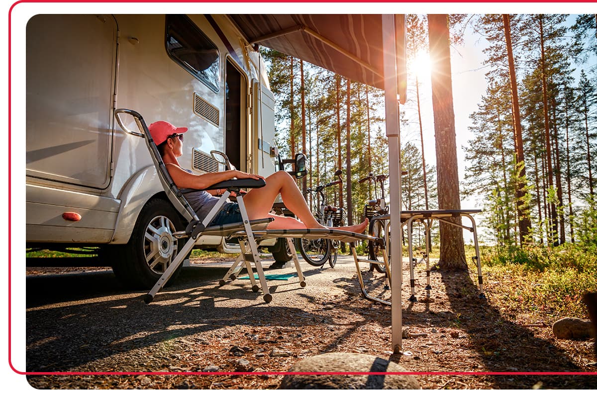 Woman relaxing with her feet propped up outside of her camper in the woods