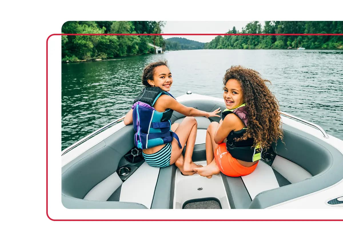 Two young girls wearing lifejackets while riding on the front of a boat in Tennessee