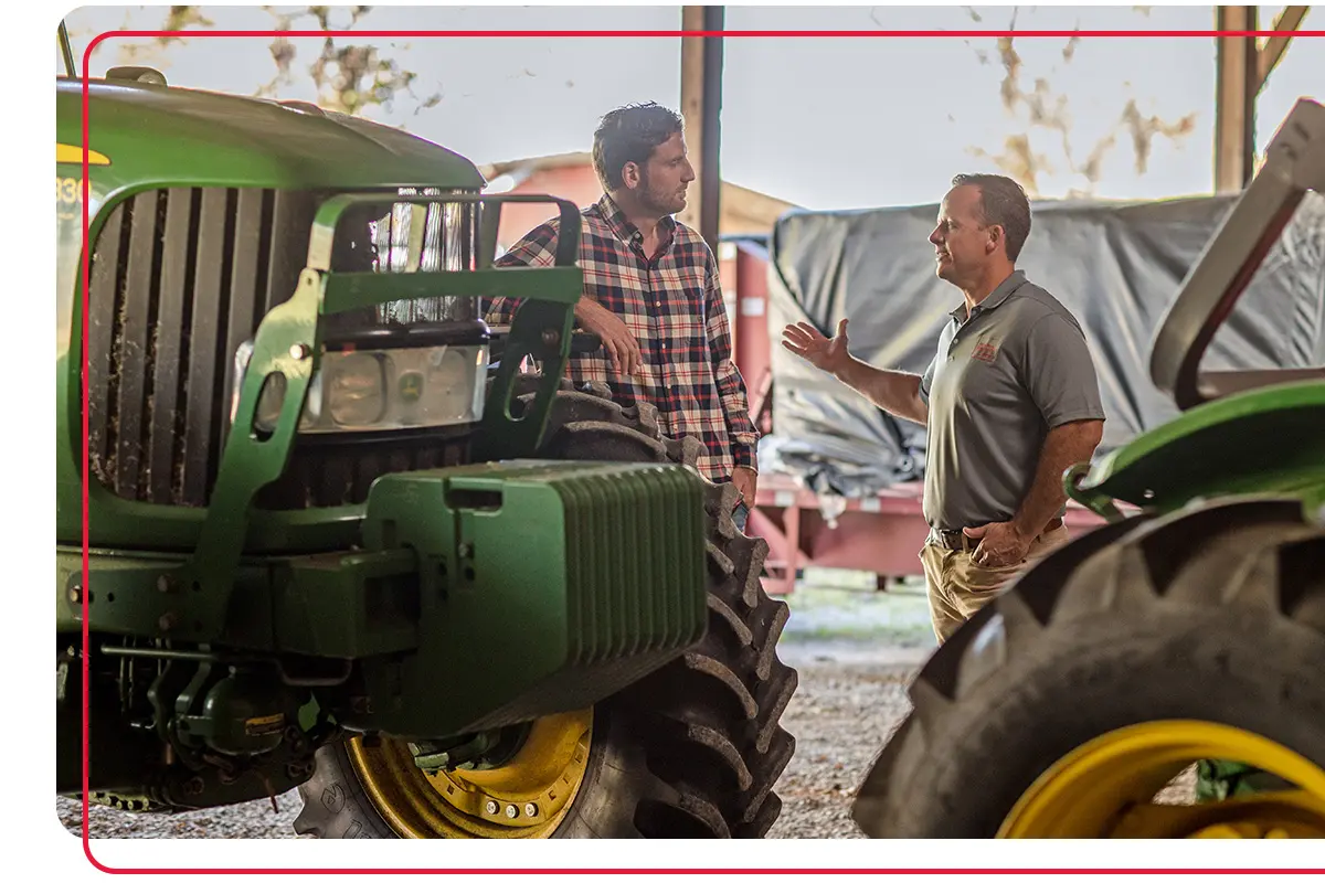 Farm Bureau Insurance of Tennessee agent meeting with local farmer in barn next to farming equipment