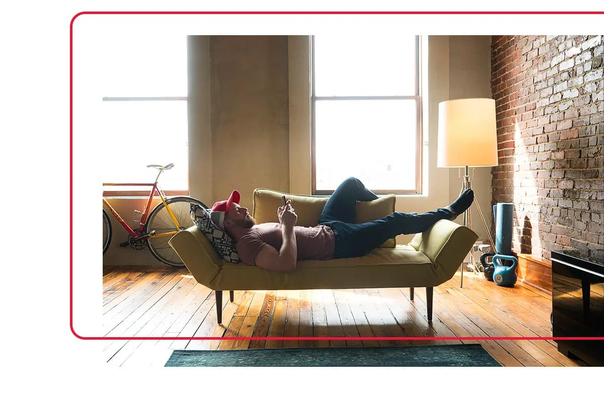 Man laying on couch and browsing phone in condo he owns