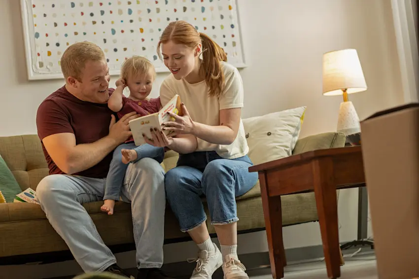 Young parents reading to their child on the couch of their home living room