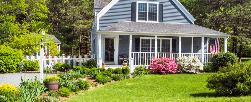 Home with front porch and well taken care of landscaping and white fence
